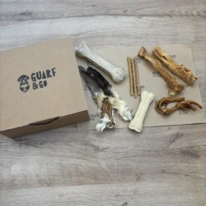 Caja Dental & Mordedor talla pequeña abierta vista desde arriba, con orejas de conejo, huesos de colágeno, huesos prensados, palitos trenzados y patas de pollo